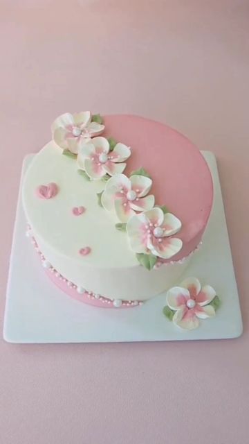 a pink and white cake with flowers on it