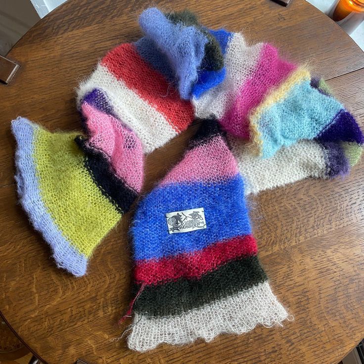 four knitted hats sitting on top of a wooden table