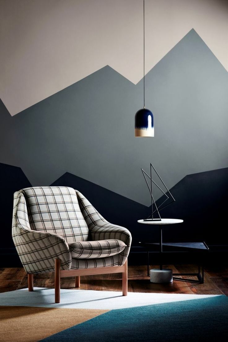 a chair and table in a room with mountains painted on the wall