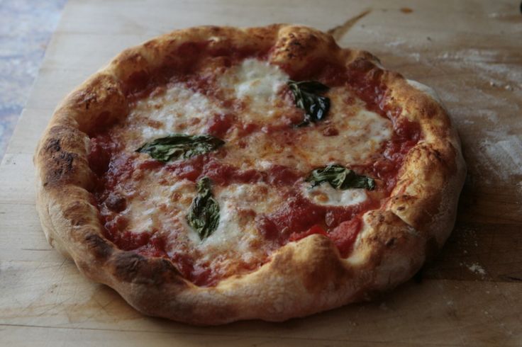 a pizza sitting on top of a cutting board covered in cheese and spinach leaves