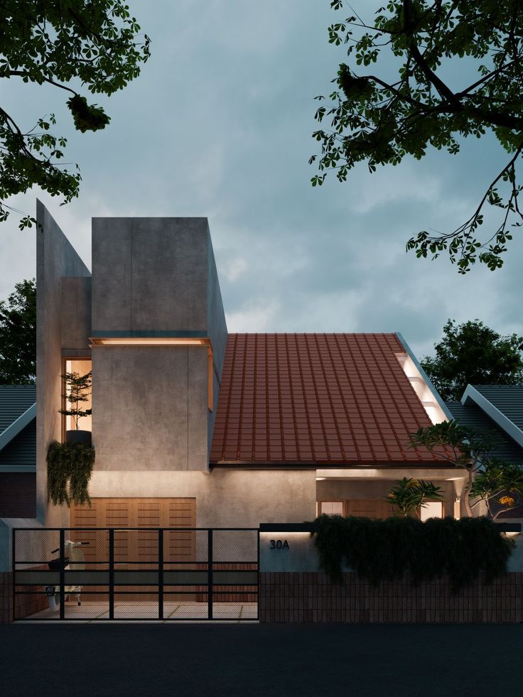 an exterior view of a modern house with red tile on the roof and windows at night