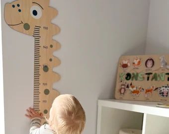 a toddler playing with a wooden growth chart