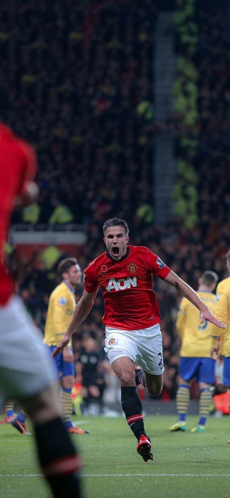 a soccer player running towards the ball during a game with other players in the background