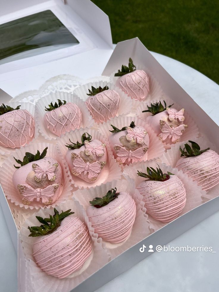 a box filled with lots of pink chocolate covered strawberries on top of a table