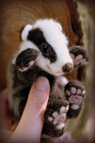 a hand holding a small stuffed animal in it's right hand and paw on the other hand