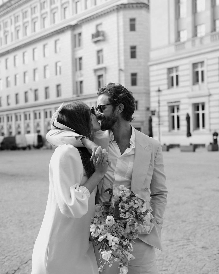 a man and woman kissing in front of a building