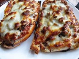 two slices of pizza sitting on top of a white plate with cheese and meat toppings