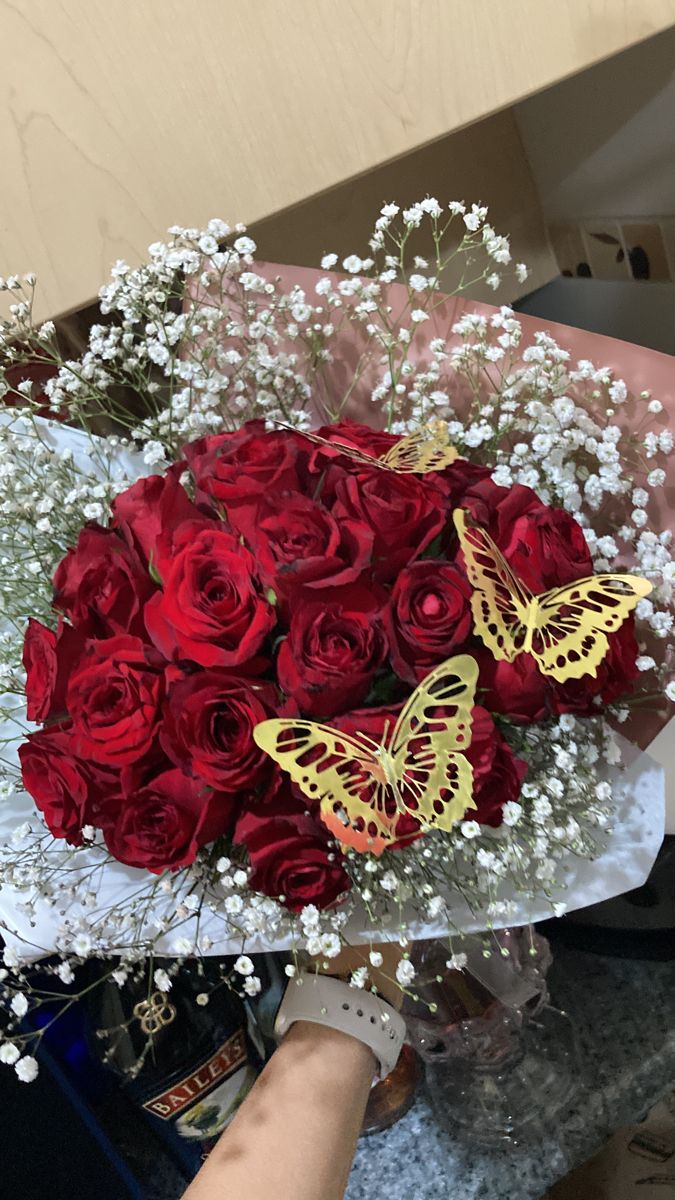 a bouquet of red roses with butterfly decorations