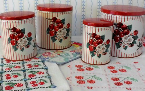 four red and white canisters with cherries on them sitting on a table