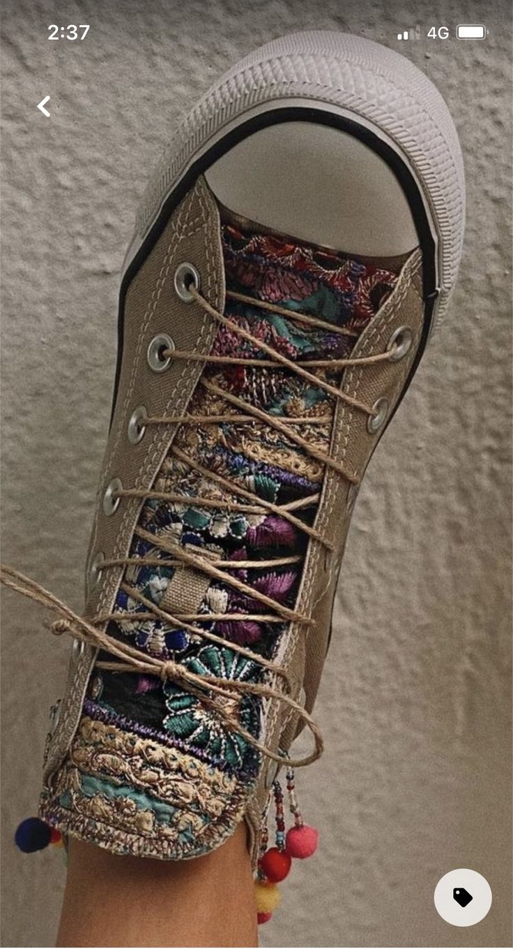 a person's hand holding up a pair of shoes with multicolored laces