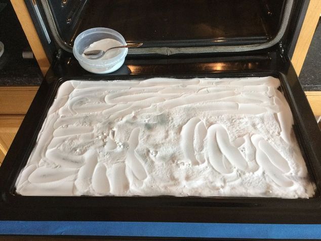 a pan filled with white frosting next to an oven