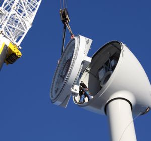 a white tower mounted to the side of a building next to a yellow crane and blue sky