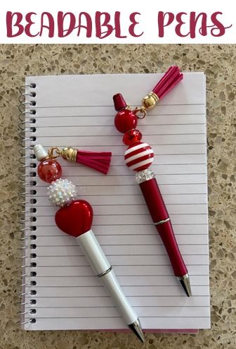 two red and white pens sitting on top of a notepad next to each other