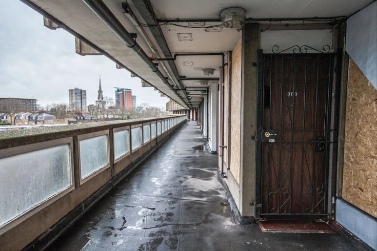 an empty hallway with boarded up doors and graffiti on the walls in front of it