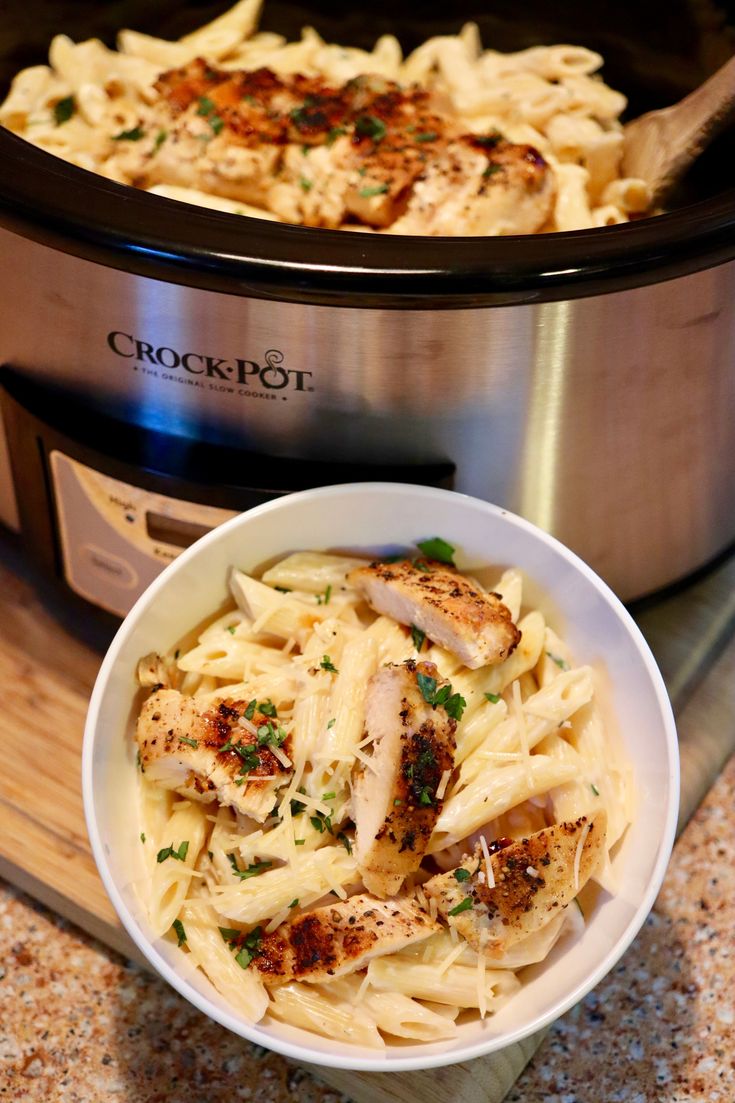 a bowl of pasta with chicken and parmesan cheese in front of an instant pressure cooker