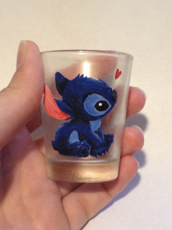 a hand holding a small glass with an image of stitchy stitching on it