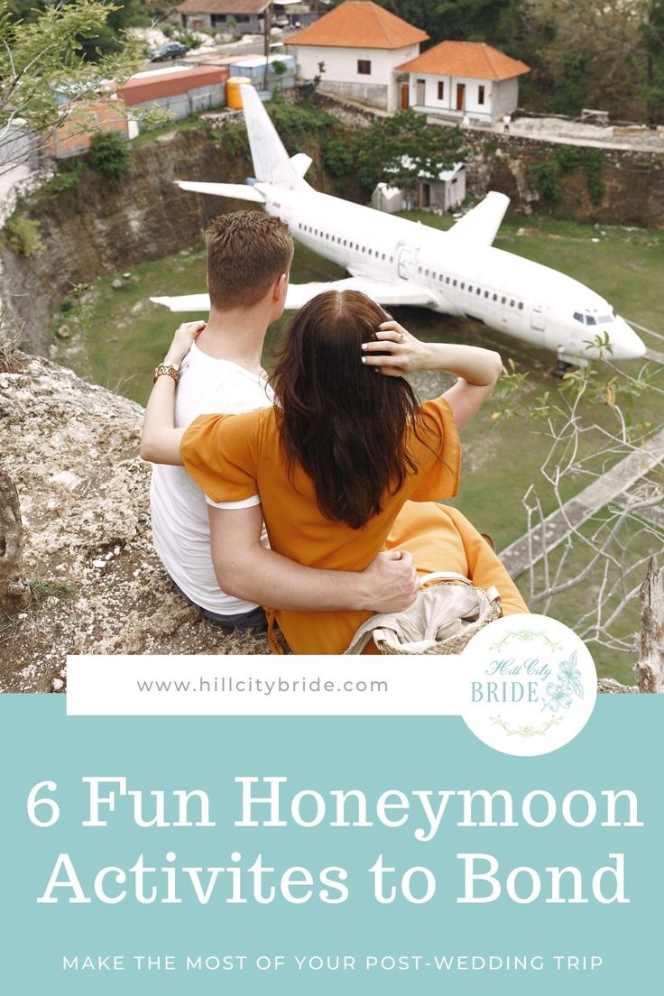 a man and woman sitting on top of a cliff looking at an airplane