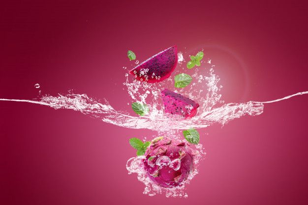 two pieces of fruit are splashing into the water on a pink background with green leaves