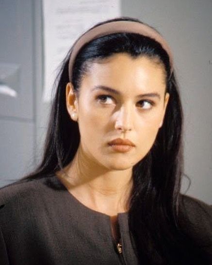 a woman with long black hair wearing a headband and looking off to the side