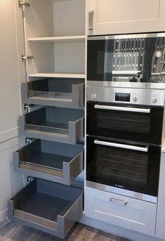 an oven built into the side of a wall in a kitchen with white cabinets and drawers