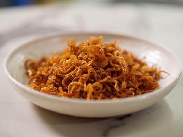 a white bowl filled with shredded carrots on top of a table