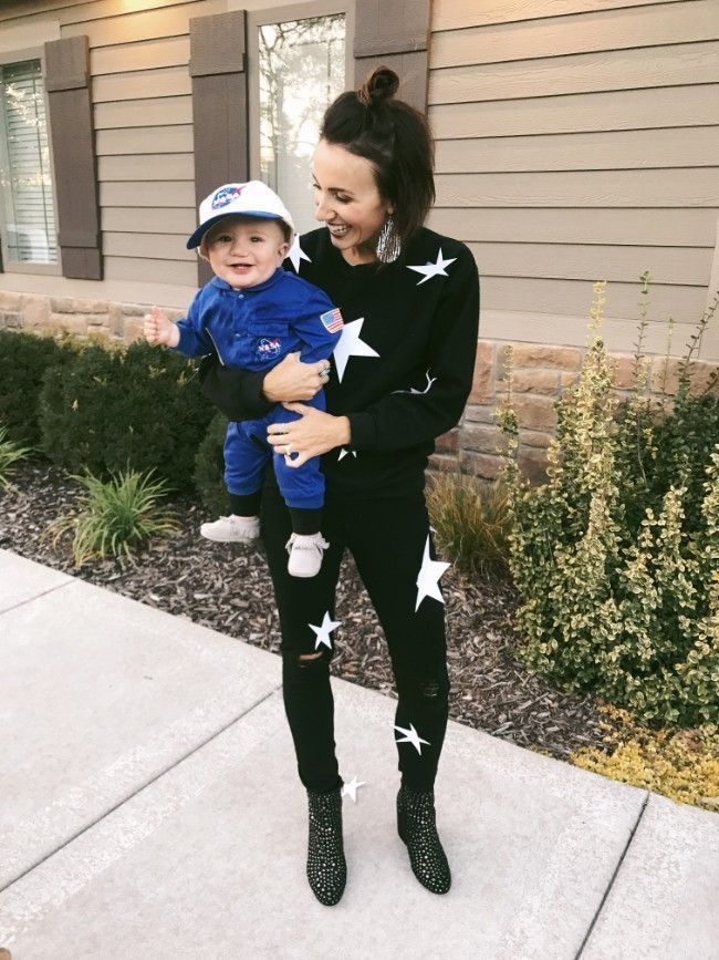 a woman holding a small child in her arms while wearing black and white stars on the sleeves