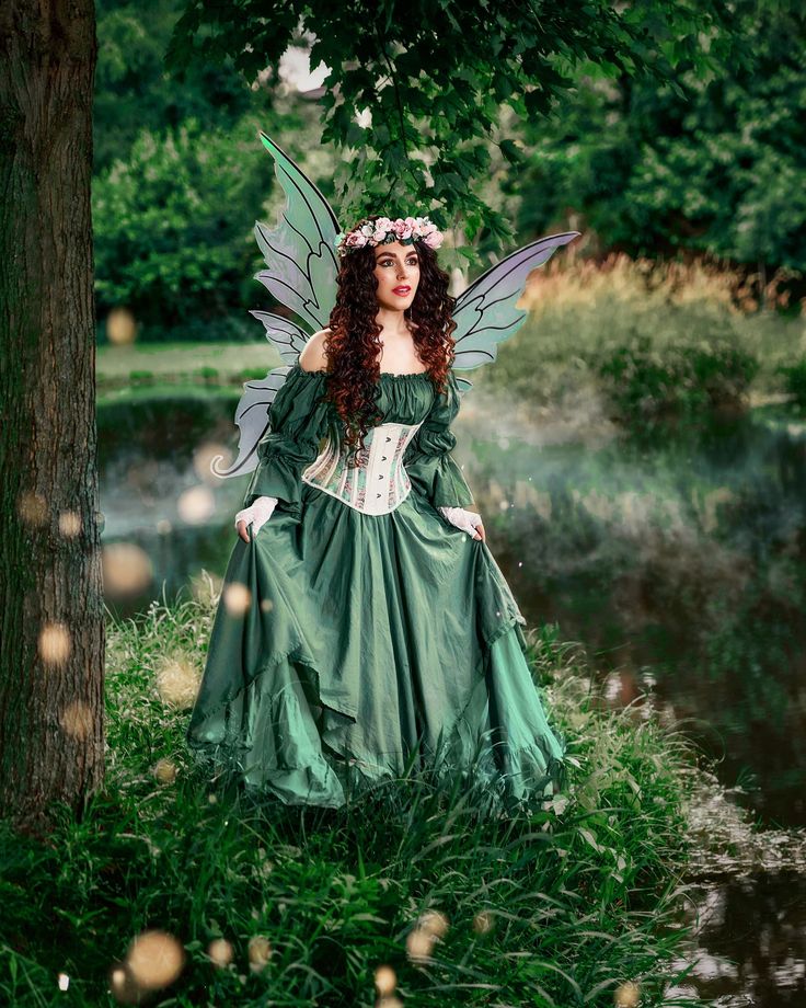 a woman dressed as a fairy standing next to a tree