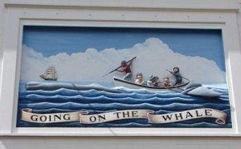 a painting on the side of a building with people in a boat and banner that says going on the whale