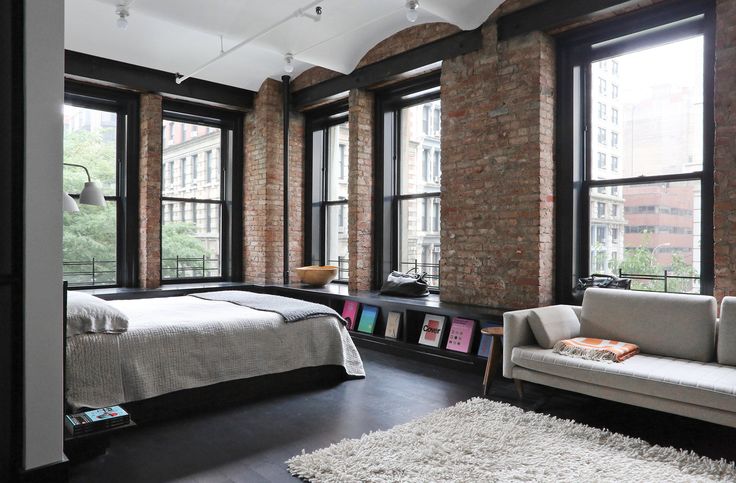 a bed room with a neatly made bed and two couches next to large windows