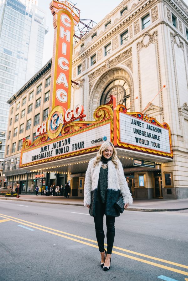 a woman walking down the street in front of a theater