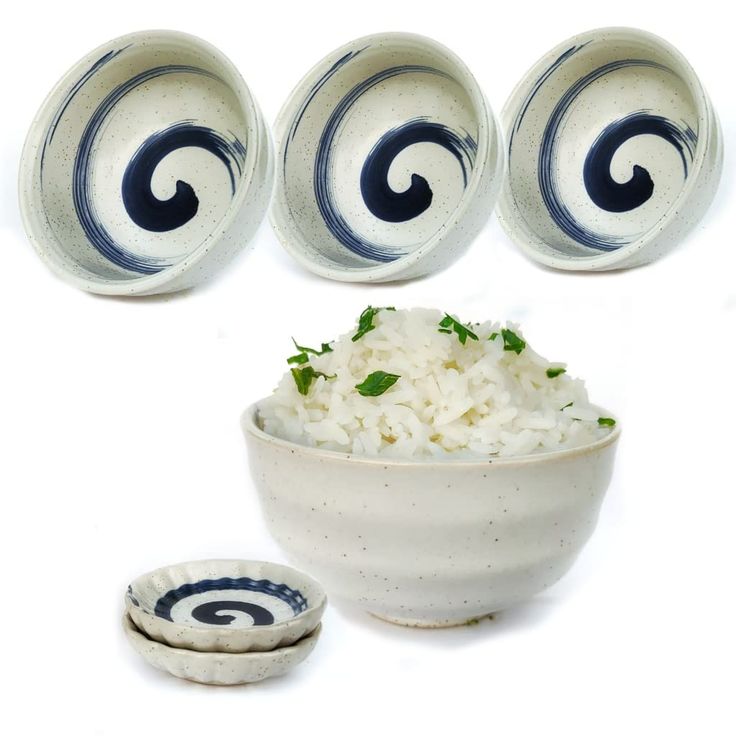 three bowls with white rice and blue swirl designs on them, next to two small plates