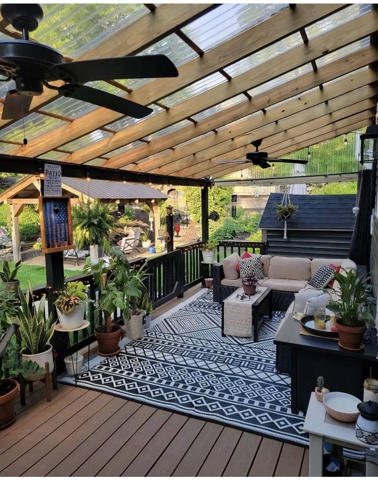 an outdoor living area with lots of plants and furniture on the deck or covered patio