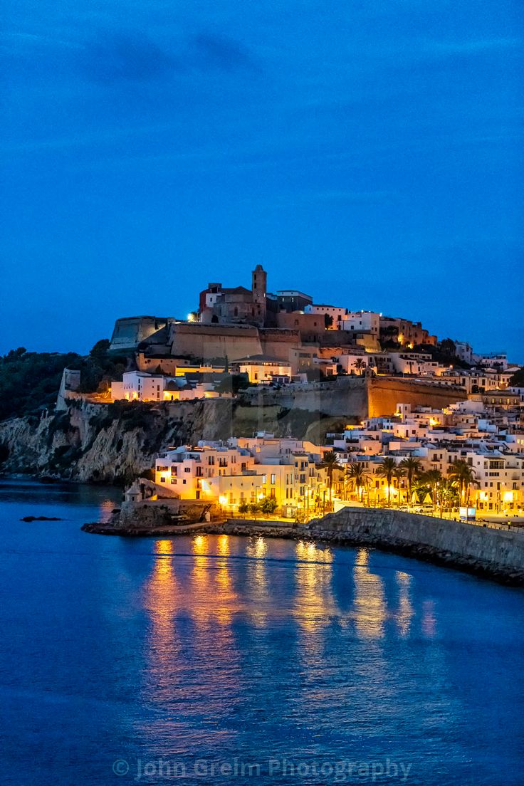 an island lit up at night with lights on it's buildings and the ocean below