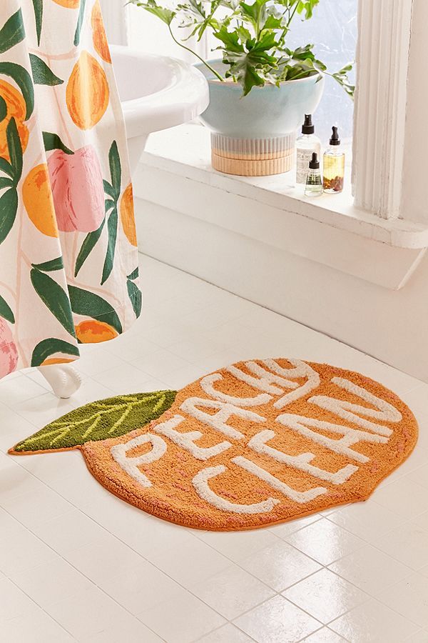 an orange door mat sitting on the floor next to a bathtub and shower curtain