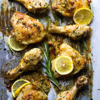 chicken with lemons and rosemary on a baking sheet