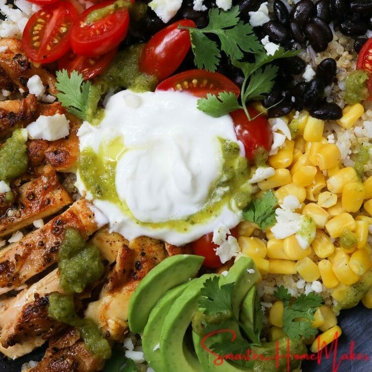 a platter with chicken, corn, tomatoes, black beans and avocado