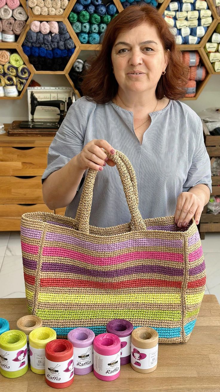 a woman is holding a large bag in front of several spools of thread