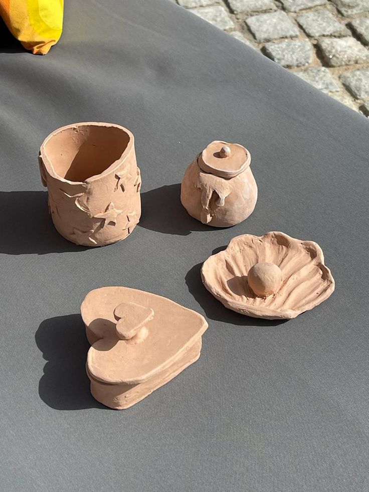 three pieces of clay sitting on top of a table next to a yellow vase and bowl