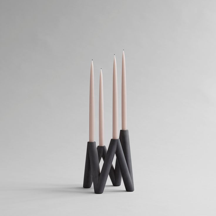 three black and white candles sitting next to each other on top of a gray surface