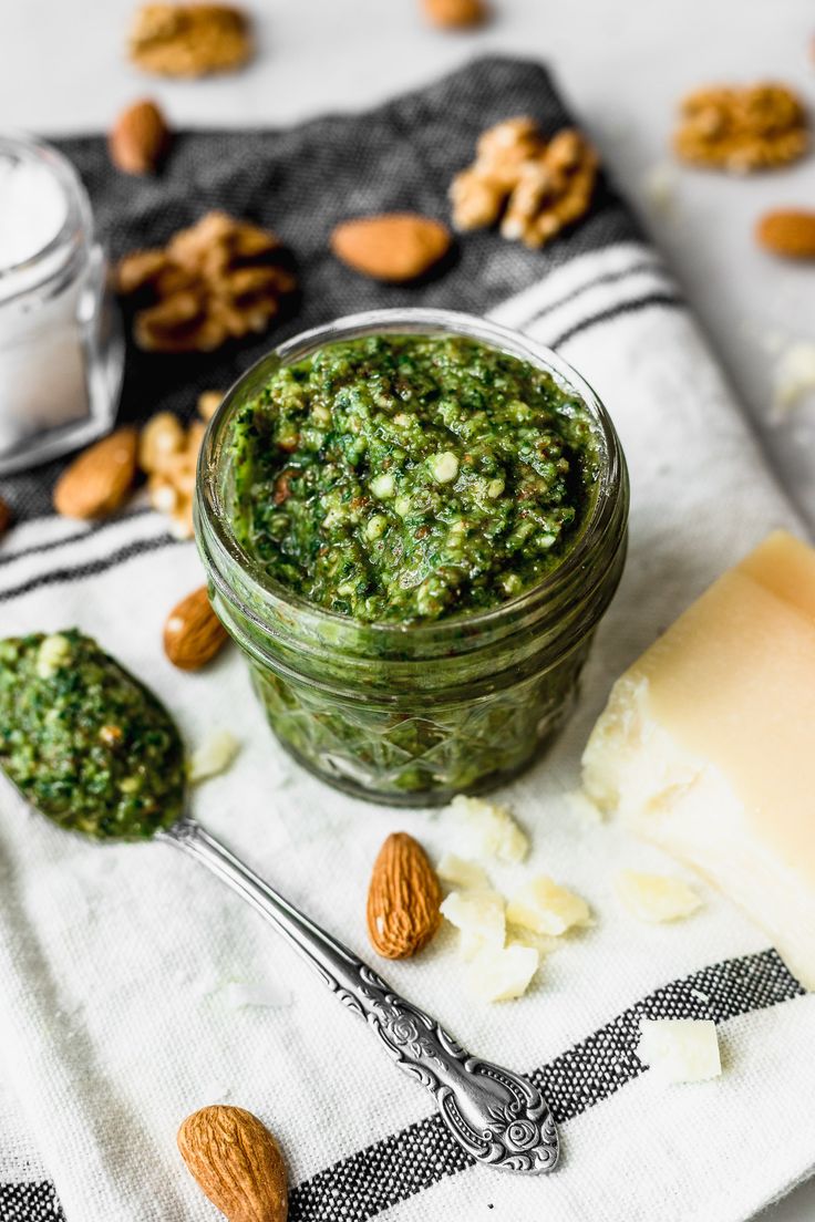 a glass jar filled with pesto and almonds on top of a white towel