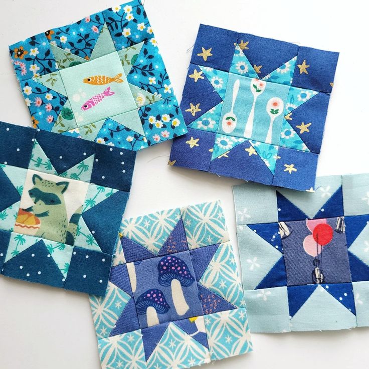 four quilted blocks with different designs on them, one is blue and the other has white stars