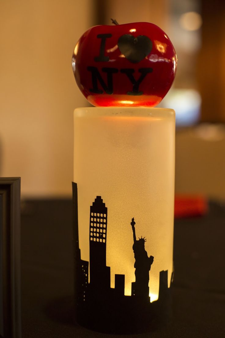 the statue of liberty is lit up with a red apple on it's top