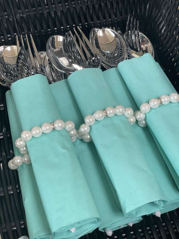 a basket filled with silverware and napkins next to green napkins on top of each other