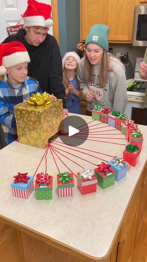 a group of people standing around a kitchen counter with presents on top of the table