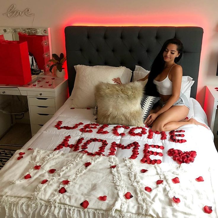 a woman sitting on top of a bed next to a pillow with the word love spelled in it