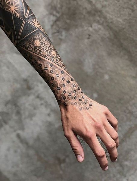 a man's arm with an intricate tattoo design on the left hand and wrist