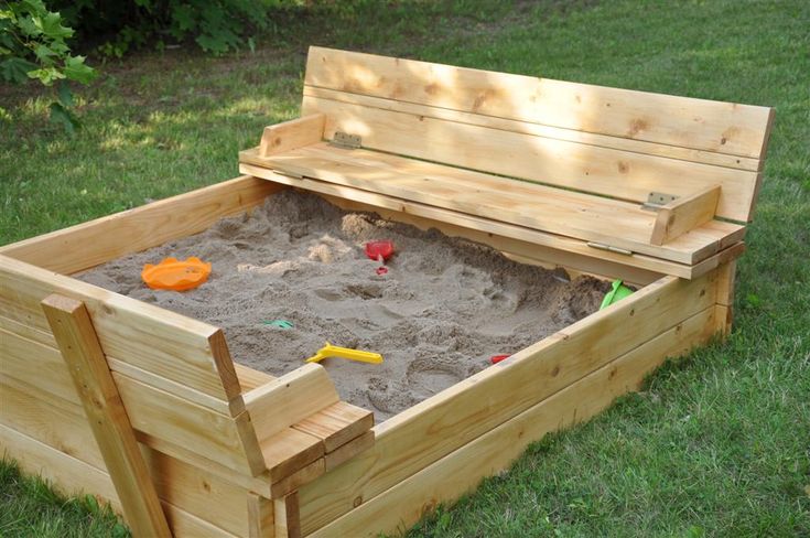 a wooden bench with sand in it on the grass