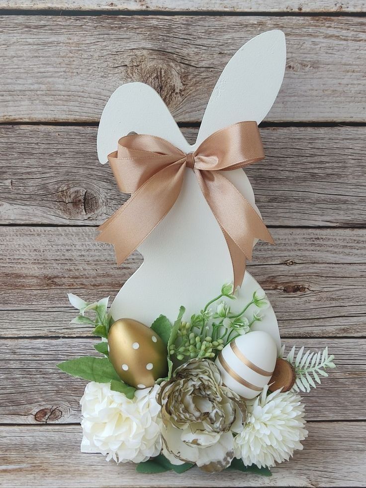 an easter decoration with flowers, eggs and a bunny's head on a wooden background