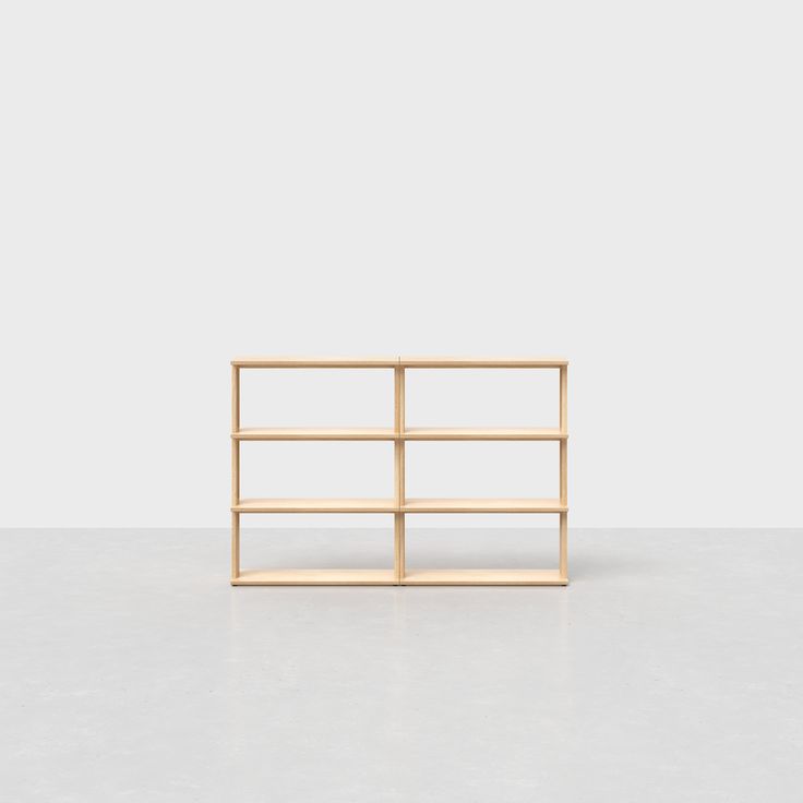 a wooden shelf with three shelves on one side and an empty wall in the background