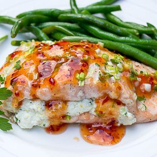 a white plate topped with meat covered in sauce and green beans